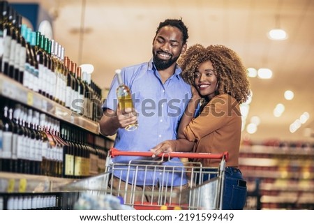 Smiling couple deciding what wine to buy in grocery store [[stock_photo]] © 