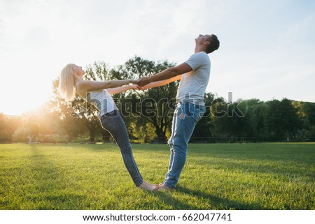 Smiling couple doing yoga exercises outdoors at the green grass on sunset 