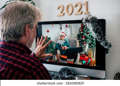 Smiling couple of elderly people talking on video call for Christmas greetings. Woman with Santa hat rests on the armchair and man greets with hand - Powered by Shutterstock