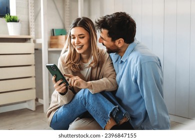 Smiling couple embracing while looking at smartphone. People sharing social media on smart phone.