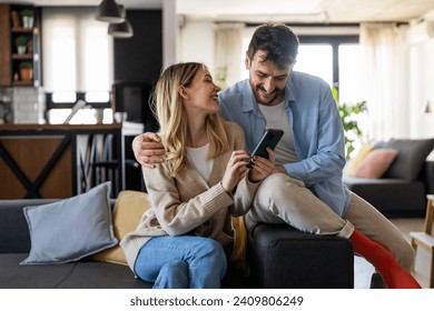 Smiling couple embracing while looking at smartphone. People sharing social media on cellphone. - Powered by Shutterstock