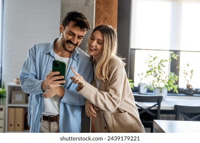 Smiling couple embracing while looking at smartphone. People sharing social media on smart phone. - Powered by Shutterstock