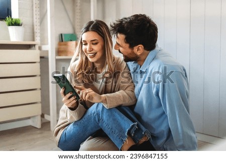 Smiling couple embracing while looking at smartphone. People sharing social media on smart phone.