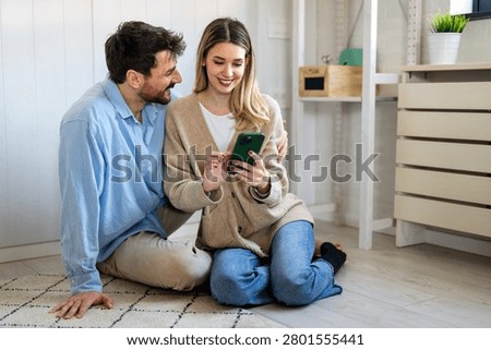 Smiling couple embracing while looking at smartphone. People sharing social media on cellphone.