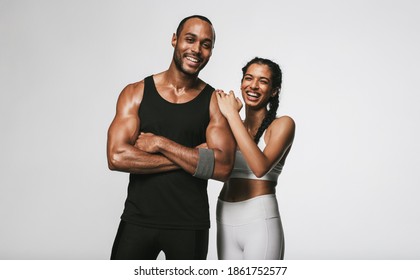 Smiling couple in fitness wear standing against white background. Fit couple relaxing after workout standing together.