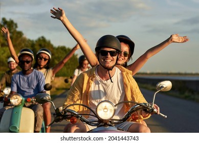 Smiling Couple Of Friends Enjoying Riding Vintage Scooters On Vacation Outside The City. Fun, Leisure Activity, Summertime, Transportation Concept