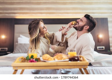 Smiling Couple Having Breakfast In Bed In Hotel Room