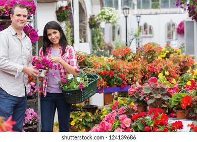 Smiling Couple Holding Basket And Bouquet In Garden Centre