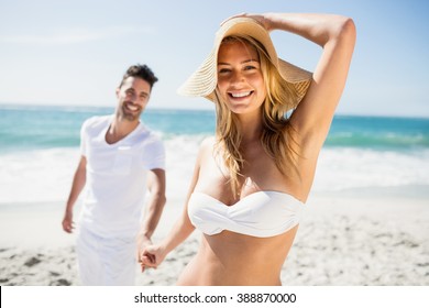 Smiling couple holding hands on the beach - Powered by Shutterstock