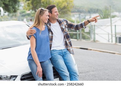 Smiling Couple Leaning On The Bonnet Of Their Car