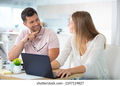 Smiling Couple Looking At Laptop In Kitchen