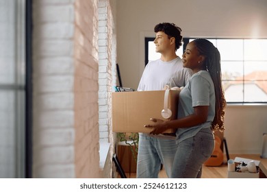 Smiling couple looking through the window while carrying cardboard boxes into their new apartment. Copy space. - Powered by Shutterstock