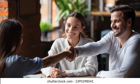 Smiling couple making successful deal, handshaking with realtor or insurance broker in cafe, family wife taking loan or mortgage, happy wife and husband at meeting with advisor or lawyer