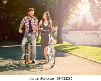 smiling couple on the bike in an alley with green trees on a sunny summer day