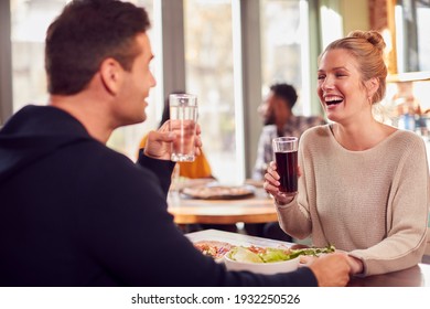 Smiling Couple On Date Enjoying Pizza In Restaurant Together