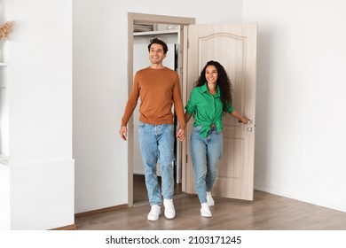 Smiling Couple Opening Door And Walking In Their Apartment, Entering New Home, Happy Cheerful Young Guy And Lady Standing In Doorway Of Modern Flat, Looking At Design Interior Together, Coming Inside