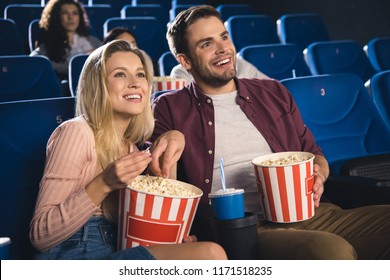 Smiling Couple With Popcorn And Soda Drink Watching Film Together In Cinema