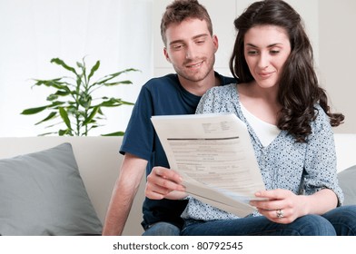 Smiling Couple Reading A Bill Arrived Via Mail