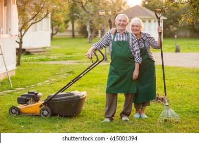 Smiling Couple Of Senior Gardeners. Happy People Outdoors, Summer. Garden Maintenance Jobs.