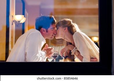 smiling couple is sitting at restaurant, view from street - Powered by Shutterstock