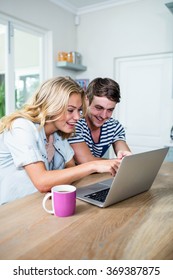 Smiling Couple Typing On Laptop At Home