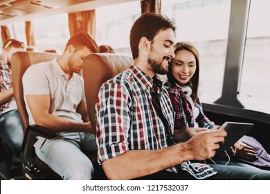 Smiling Couple Using Digital Tablet in Tour Bus. Young Handsome Man and Beautiful Woman Sitting on Passenger Seats of Tour Bus and Using Touchscreen Device. Happy Travelers on Trip - Powered by Shutterstock