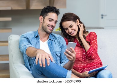 Smiling Couple Using Phone At Home