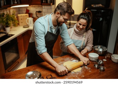 Smiling couple in a warm kitchen, rolling out dough for baking. The atmosphere is cozy and inviting, with various baking tools and ingredients spread across the wooden counter