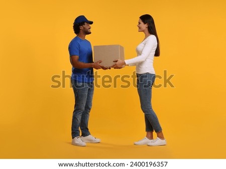 Smiling courier giving parcel to receiver on orange background