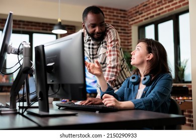 Smiling coworker talking with friendly 3D artist about electronic arts and digital graphics developing. Creative agency diverse employees in brainstorming production ideas.