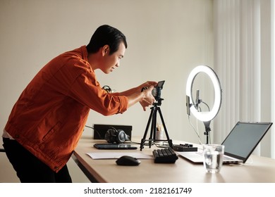 Smiling Creative Blogger Changing Camera Lens To Film Review In His Home Studio