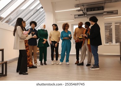 Smiling creative workers talking in office; Multiethnic group of smiling creative workers standing and talking in modern office