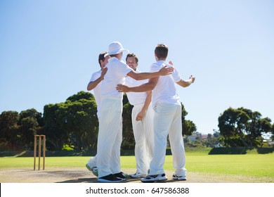 Smiling cricket players standing at field against clear sky - Powered by Shutterstock