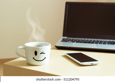 Smiling cup of coffee, smartphone and laptop on the desk - Powered by Shutterstock