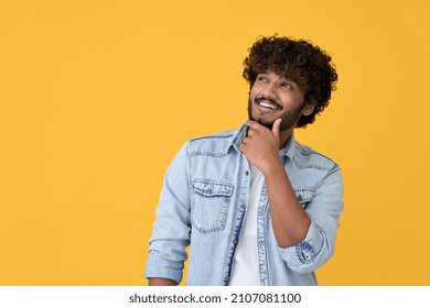 Smiling curious young indian man holding hand on chin looking interested aside at copy space isolated on yellow background thinking of shopping opportunities, planning purchase or dreaming concept. - Shutterstock ID 2107081100