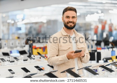 Smiling customer browsing smartphones while selecting a new mobile device in an electronics store, enjoying the shopping experience