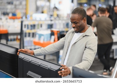 Smiling customer comparing various televisions while shopping in a consumer electronics store, evaluating options for the best choice