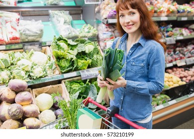 Smiling customer holding a leek in a supermarket - Shutterstock ID 573210199