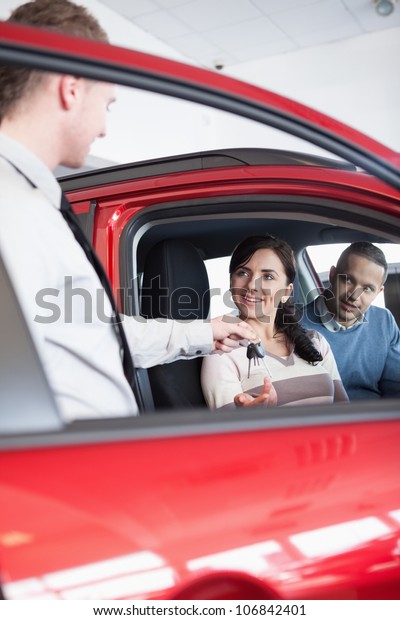 Smiling\
customer receiving car keys from a\
salesman
