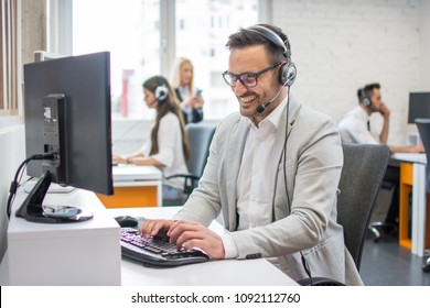 Smiling customer service executive with headset working in call center.