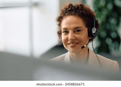 Smiling customer service representative working on a computer at call center and looking at camera. - Powered by Shutterstock