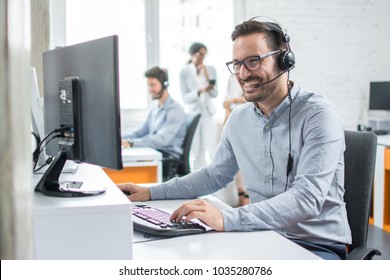 Smiling customer support operator with hands-free headset working in the office. - Shutterstock ID 1035280786