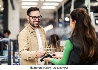 A smiling customer using credit card in supermarket at checkout. - Shutterstock ID 2149839505