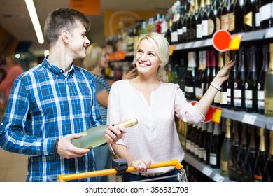 smiling Ã?Â�ouple of customers purchasing at wine section in supermarket