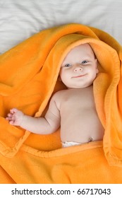 Smiling Cute Baby Boy Wrapped In Orange Towel