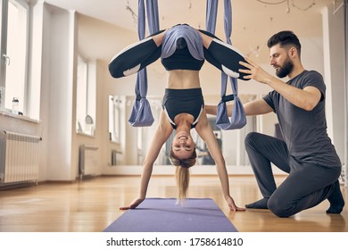 Smiling cute fit young blonde lady doing an anti-gravity exercise assisted by a qualified coach - Powered by Shutterstock
