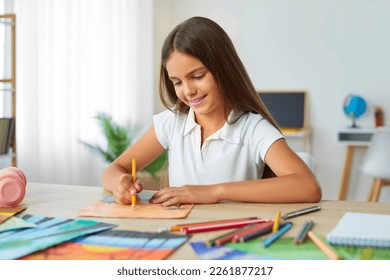 Smiling cute girl drawing, painting picture with interest using colorful pencils sitting at table at home. Preteen girl in white polo shirt looking at picture. Education, art, homeschooling concept. - Powered by Shutterstock