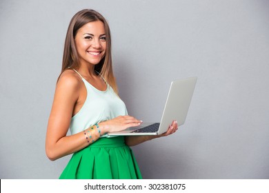 Mosolygó aranyos lány használ laptop felett szürke háttér és látszó-on kamera
