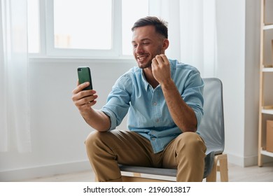 Smiling Cute Happy Talking About His Business To Audience Attractive Young Man Looks At Screen Hold Phone Record Video Review At Home. New Profession Online Influencer Blogger Concept