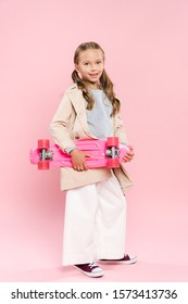 Smiling And Cute Kid Holding Penny Board On Pink Background 